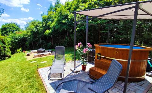 a hot tub and two chairs under an umbrella at The WoodHouse Vendégház in Nagymaros