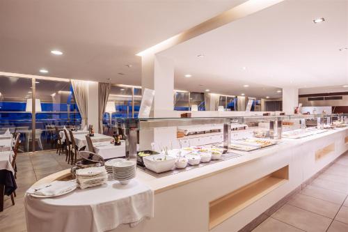 ein Restaurant mit einem Buffet mit weißen Tischen in der Unterkunft Hotel Simbad Ibiza in Talamanca