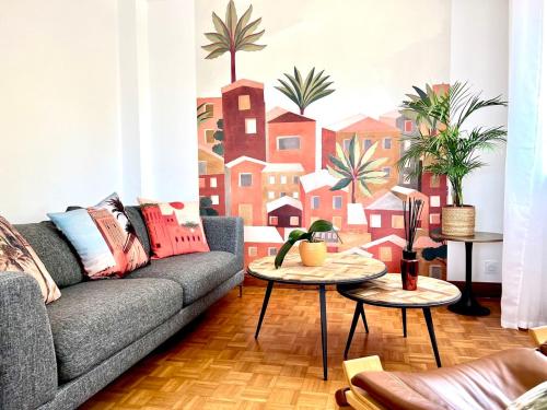 un salon avec un canapé et une fresque murale représentant des bâtiments dans l'établissement L ÂME VOYAGEUSE, Raffinée, 2-8 personnes, 15 min des plages, à Baye