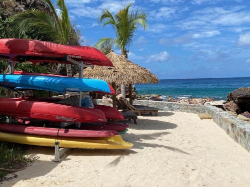 a group of surfboards sitting on a beach with an umbrella at Lime in de Coconut Villa in Cruz Bay