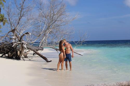 a man and a woman standing on a beach at Finimas Residence in Thimarafushi