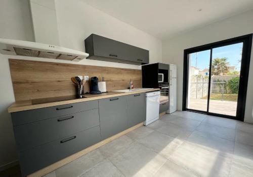 une cuisine avec des armoires grises et une grande fenêtre dans l'établissement Maison hyper centre 3 chambres, à Fouras