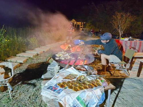 a man is cooking food on a grill at Ngài Sảng Homestay in Làng Cac