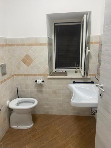 baño con aseo y lavabo y ventana en Al Romito, en Santo Padre