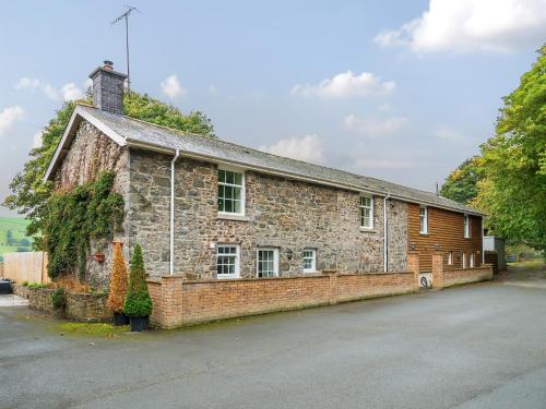 an old brick building with a chimney on a street at Old Rectory Cottages in Aberhafesp