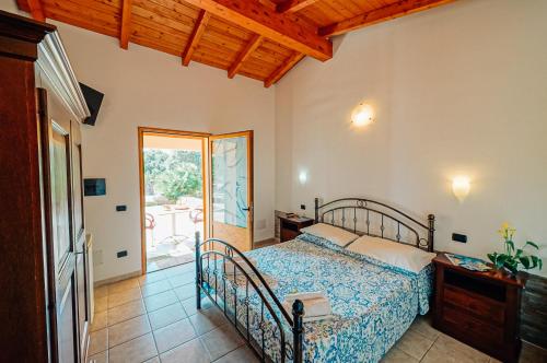Schlafzimmer mit einem Bett und einer Tür zu einer Terrasse in der Unterkunft Agriturismo Rocce Bianche - Porticato in Arbus