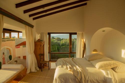 a bedroom with a bed and a large window at Casa Balandra: Experiential Guesthouse in Pòrtol