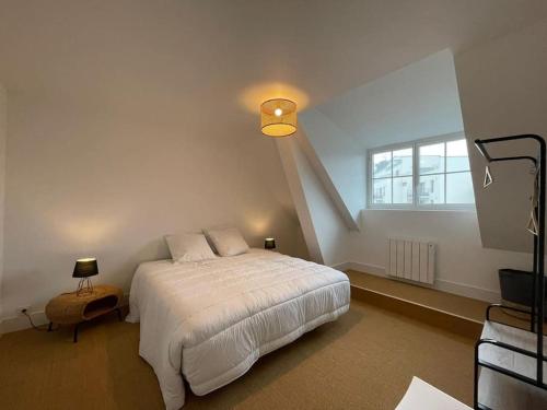 a bedroom with a white bed and a window at Grand appartement renové centre historique proche plages in Perros-Guirec