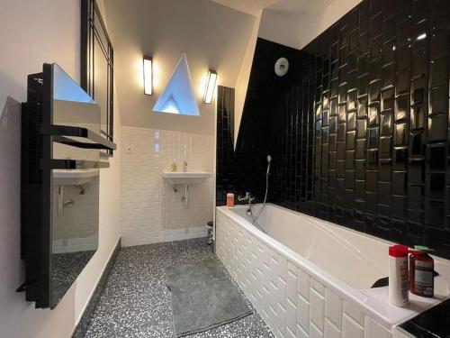 ein Badezimmer mit einer weißen Badewanne, einem Waschbecken und einem Waschbecken in der Unterkunft Grand appartement renové centre historique proche plages in Perros-Guirec