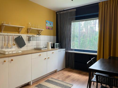 eine Küche mit weißen Schränken, einem Tisch und einem Fenster in der Unterkunft Cozy city center apartment in Visaginas