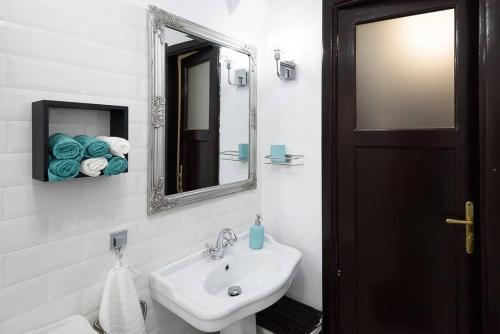 ein weißes Badezimmer mit einem Waschbecken und einem Spiegel in der Unterkunft Studio Villa Floreasca in Bukarest