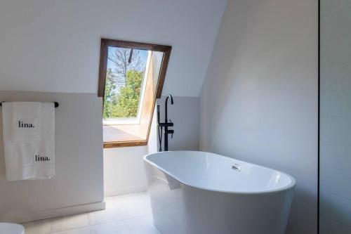 a white bathroom with a tub and a window at Emberwood Lodge - Luxury Cabin, Kid Friendly in Catskill