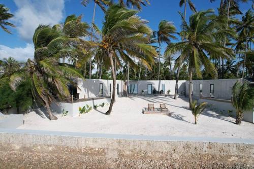 a building on the beach with palm trees at The Zanzibar Beach House-West in Pingwe