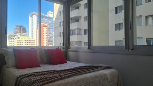 łóżko z czerwonymi poduszkami w pokoju z oknem w obiekcie VN Frei Caneca w São Paulo