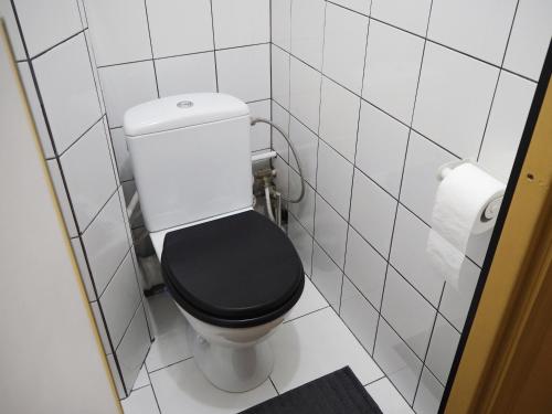 a bathroom with a black toilet with a toilet paper roll at Cozy city center apartment in Visaginas