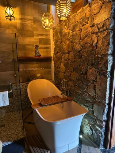 a bath tub in a bathroom with a stone wall at Casa Miura Hotel Boutique in Ajijic
