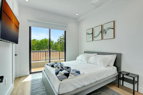 a white bedroom with a bed and a large window at Fresco 1, Modern Design, Brand New Construction and Furniture in Miami