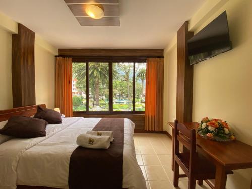 a bedroom with a bed and a desk and a television at Hostal Magdala in Baños