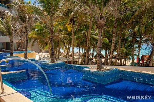 a swimming pool with palm trees in a resort at Flamingo Cancun All Inclusive in Cancún
