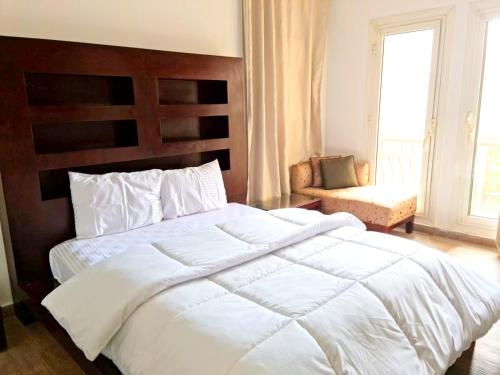 a bedroom with a large white bed and a chair at Two Bedroom Luxury Apartment in New Cairo in Cairo