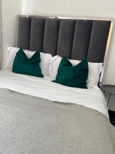 a large bed with two green pillows on it at Borehamwood stay in Borehamwood