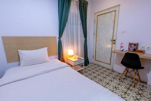a bedroom with a bed and a desk and a chair at BELVA huis in Bogor