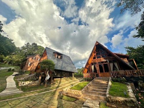 two large wooden buildings with stairs in a field at Ban Kaew Mo Ra Glamping & Restaurant in Pang Mapha