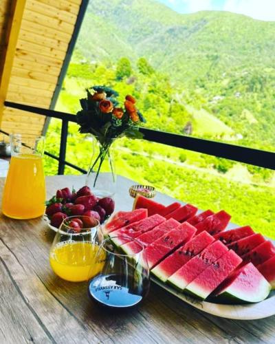 a table with a plate of watermelons and fruit on it at Eco cottage sunrise merisi in Merisi