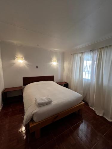 ピカにあるHospedaje la Florentinaのベッドルーム1室(白いシーツが敷かれた大型ベッド1台、窓付)