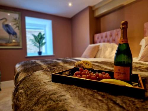 a bottle of champagne and a tray of fruit on a bed at Hamilton - Lord William in Scorton