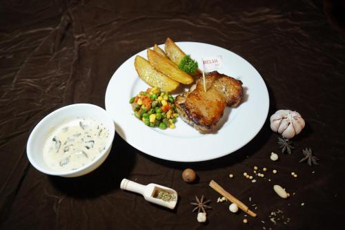 a plate of food with meat and potatoes and a bowl of dip at BELVA huis in Bogor