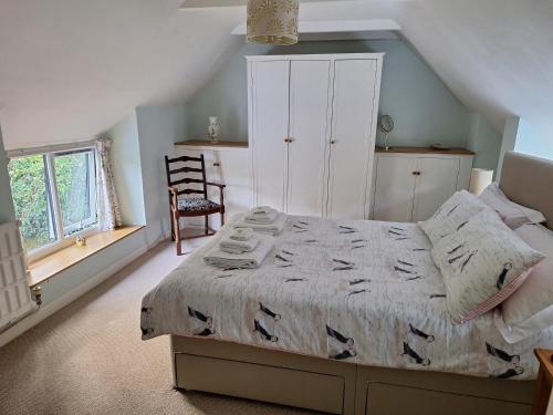 a bedroom with a bed and a chair in it at Lane End Cottage in Honiton