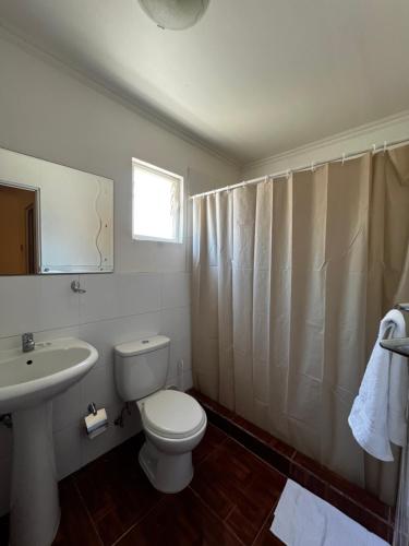 a white bathroom with a toilet and a sink at Hospedaje la Florentina in Pica