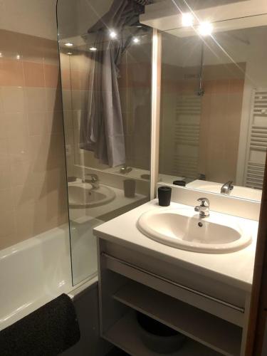 une salle de bain avec un lavabo, un miroir et une baignoire dans l'établissement VALMEINIER 1800, à Valmeinier