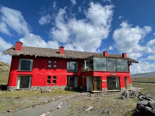 a red house in the middle of a field at Hotel Tambopaxi in Machachi
