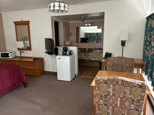 a room with a bed and a kitchen with a television at Redwood Arms Motel in Paonia
