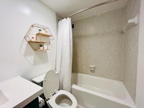 a white bathroom with a toilet and a bath tub at Oceanview Beachfront Condo on Tides Resort in Hollywood