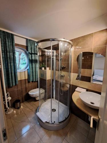 a bathroom with a shower and a toilet and a sink at Orient Apartmanház in Eger