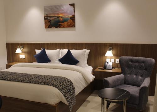 a hotel room with a bed and a chair at Duqm Express Hotel in Duqm