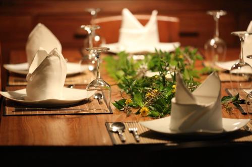 a wooden table with white plates and napkins on it at Stone Well Garden Villa in Hikkaduwa