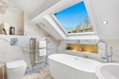 a bathroom with a large white tub and a window at Stunning 3 Bed Duplex Apartment in the heart of West Hampstead in London