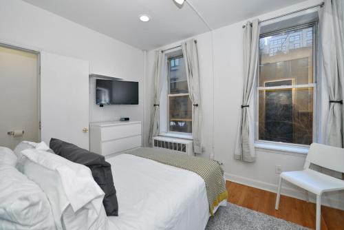 biała sypialnia z łóżkiem i telewizorem w obiekcie The Loft Life 3BR in NYC! w Nowym Jorku