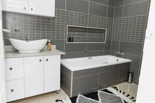 a bathroom with a sink and a bath tub at Sapphire Guesthouse in Pinetown