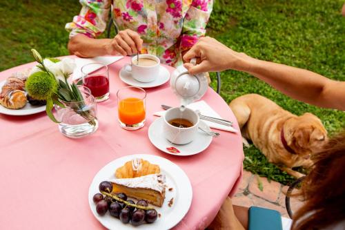 a woman sitting at a pink table with a dog drinking coffee at Hotel Sant'Andrea in Ravenna