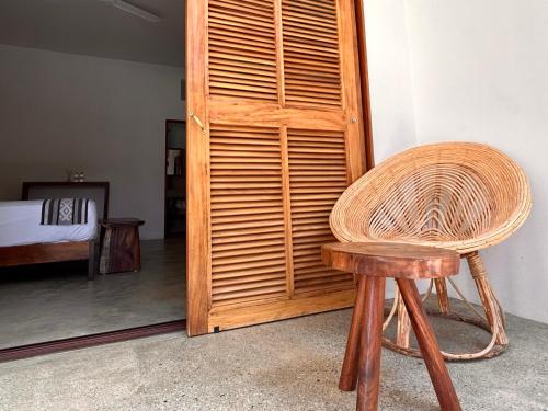 a wicker chair sitting next to a wooden door at Hotelito Zicatela in Brisas de Zicatela