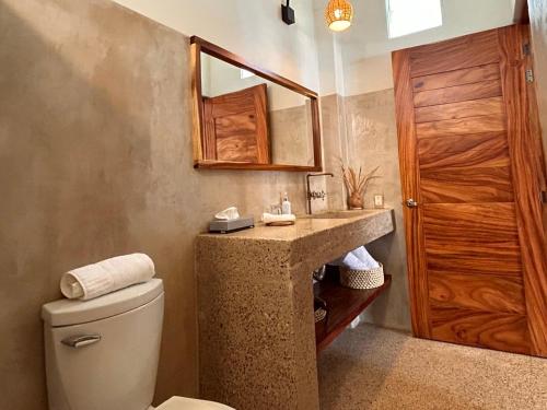 een badkamer met een wastafel, een toilet en een spiegel bij Hotelito Zicatela Cam a la Cruz 70938 Puerto Escondido Oax in Brisas de Zicatela