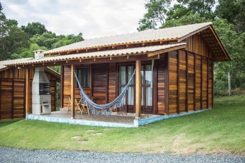 Cabaña de madera con hamaca en el patio en Verde & Mar Chalés, en Penha