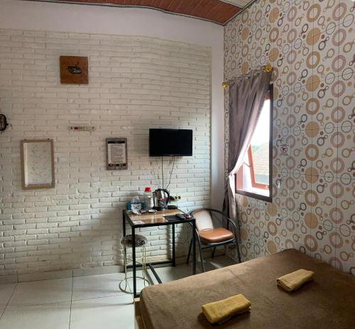 a bedroom with a desk and a tv on a brick wall at Butterfly Kost Tulungagung in Ngantru