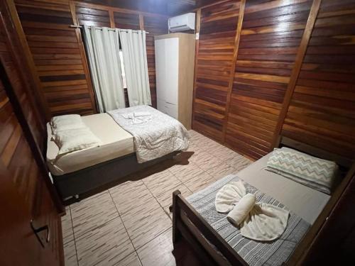 Habitación pequeña con 2 camas y paredes de madera. en Verde & Mar Chalés, en Penha