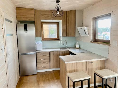 a kitchen with a stainless steel refrigerator and wooden cabinets at Domek Wester House Fuleda z Sauną Jacuzzi i Kominkiem in Giżycko